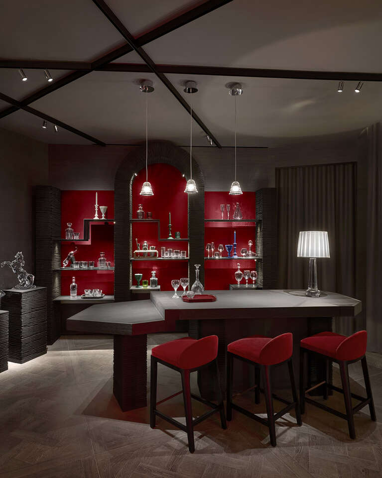 Baccarat space designed as a living room with table, chair and Baccarat products on shelves